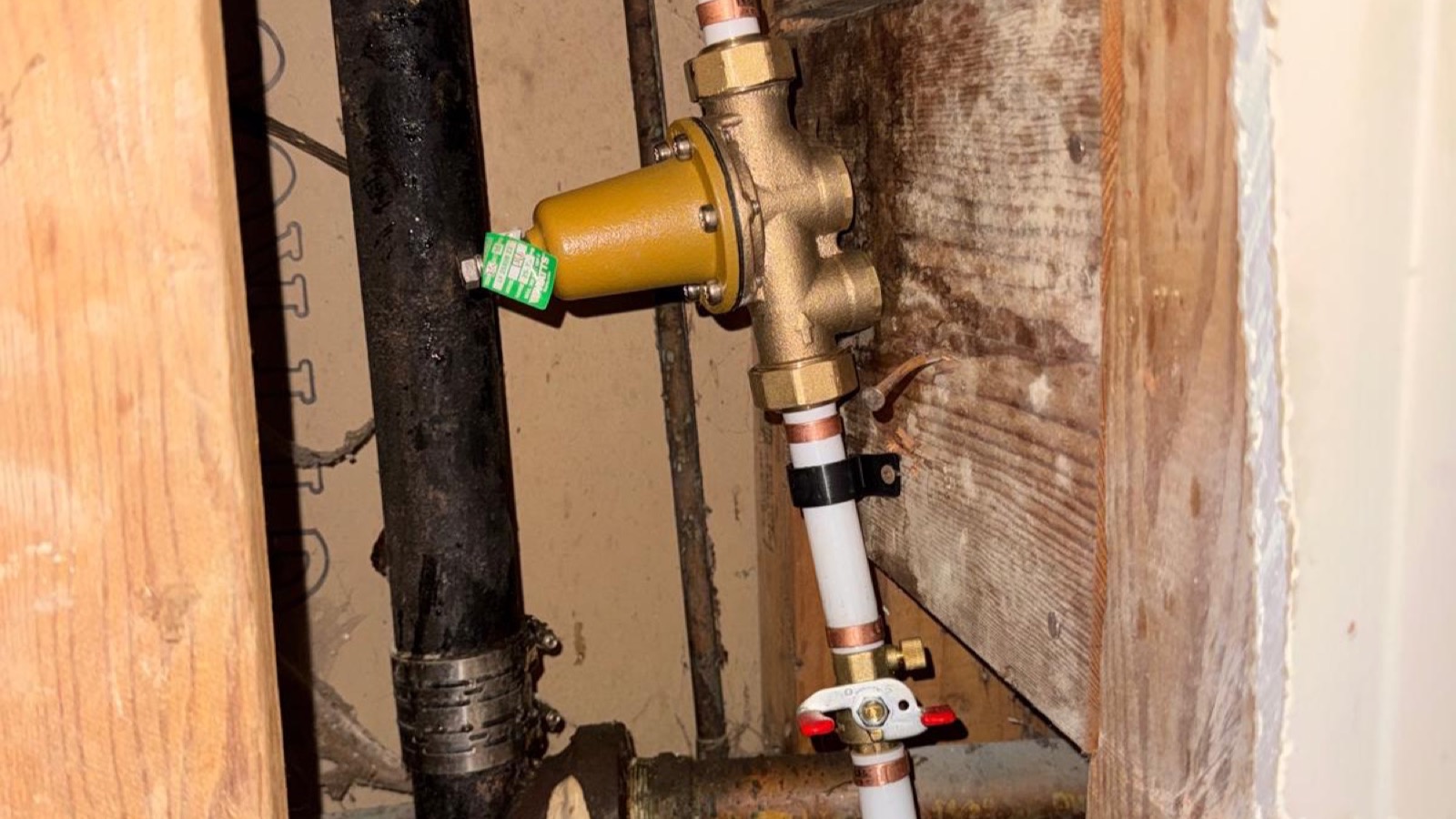 New plumbing lines and a pressure valve installed inside an open wall